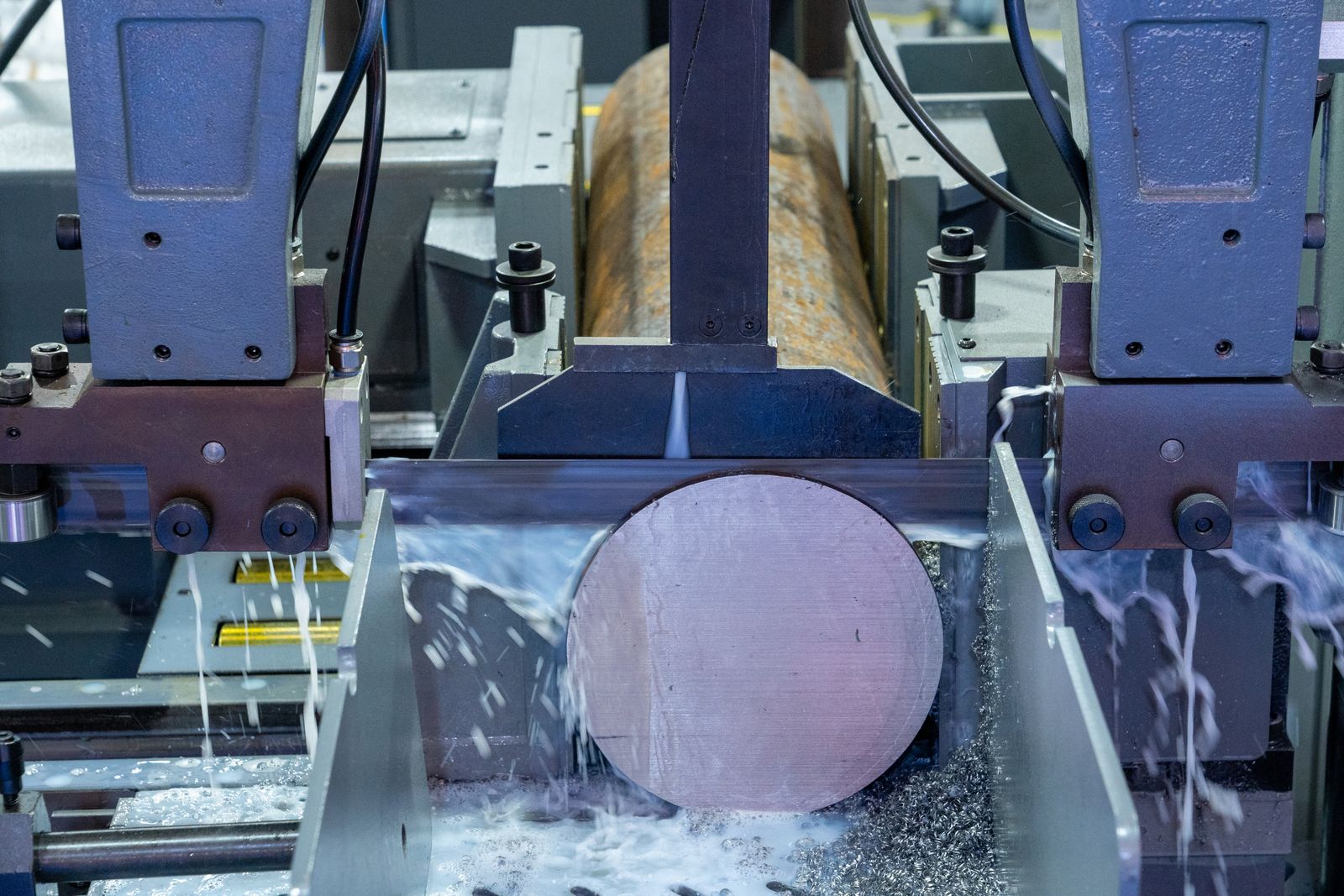 CNC machining center turning a large steel billet with coolant